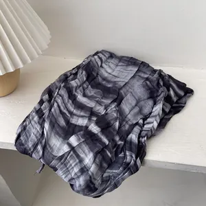Détail de la texture plissée en dégradé noir et gris d'une écharpe en coton et lin
