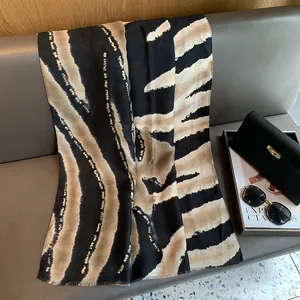 Détail d'une écharpe zébrée avec fils dorés drapée sur un canapé gris élégant