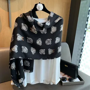 Detail of black cotton scarf with cartoon teddy bear patterns and classic plaid details