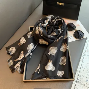 Detailed view of black scarf featuring check pattern teddy bear prints and fringe edges