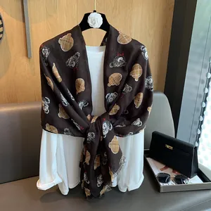 Detail of soft cotton-linen scarf with brown teddy bear print styled over a white shirt
