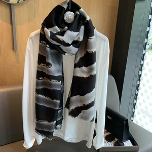 Détail d'écharpe à rayures gris et noir avec fils dorés brillants et bords effilochés