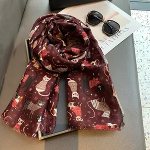 Detailed close-up of a burgundy linen scarf with cute cartoon cats and snowflake motifs