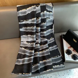 Détail d'une écharpe rayée noir et blanc avec fils dorés sur un canapé en cuir