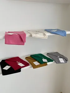 Pañuelos triangulares de lana doblados en colores rosa, beige, azul y granate