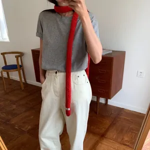 Slim red knit scarf with fringe detail and white label shown in a lifestyle selfie