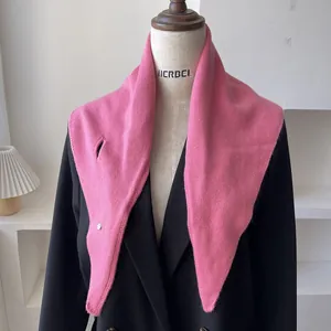 Pañuelo triangular rosa de lana con botón de cierre sobre una chaqueta negra