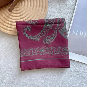 Deep burgundy paisley square scarf displayed on plush fabric with rustic lifestyle props