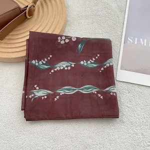 Detail of dark red linen scarf featuring lily of the valley print and neat machine edges