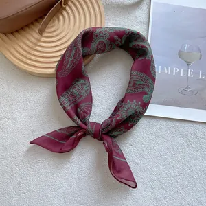 Close-up of knotted burgundy paisley silk scarf with glossy satin texture and green patterns