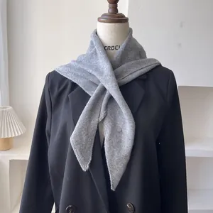 Detalle de bufanda triangular de punto gris 50% lana sobre una chaqueta tipo blazer