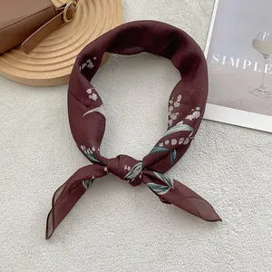 Detailed view of dark red cotton linen scarf with floral print tied in an elegant knot