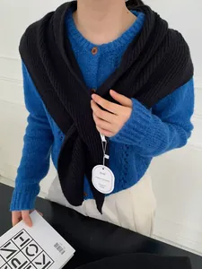 Close-up of royal blue knit cardigan with amber buttons and black shoulder shawl detail