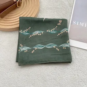 Detail of dark green linen-blend scarf featuring delicate floral prints and fine edge stitching