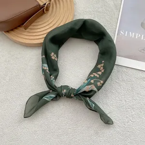 Detailed view of dark green silk scarf with white lily of the valley floral patterns