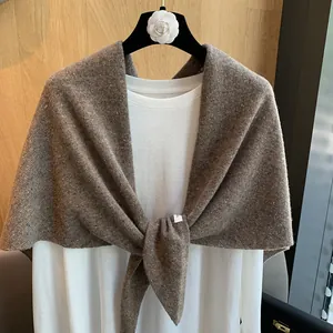 Detail of a brown knit 100% wool shawl with colorful flecks on a white t-shirt