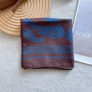 Silk square scarf with blue paisley print on brown background, spread out for display