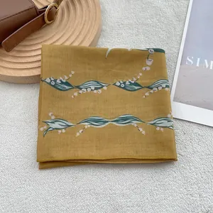 Detail of yellow cotton linen scarf featuring lily of the valley floral patterns