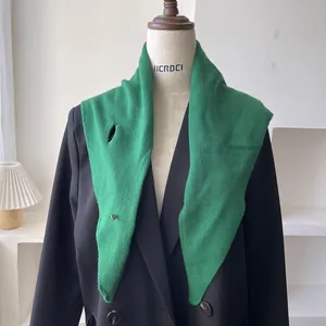 Detalle de bufanda triangular de lana tejida verde hierba con diseño de ojal para sujeción