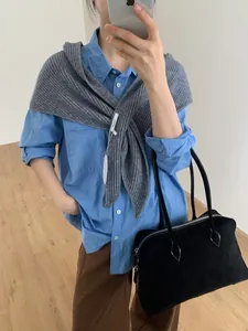 Mirror selfie showing a grey knitted shawl layered over a blue button-down shirt and brown pants