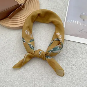 Detail of a ginger yellow silk scarf with delicate floral print on a soft plush background