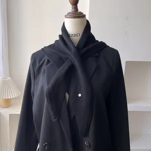 Detalle de bufanda triangular de punto en mezcla de lana negra con botón blanco en maniquí