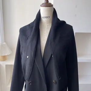 Detalle de una chaqueta negra cruzada combinada con un suave chal de lana de punto fino