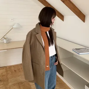 Classic dark brown wool coat styled with a bright orange ribbed knit long scarf and jeans