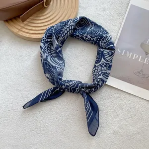 Detail view of navy blue square scarf with vintage butterfly and geometric patterns