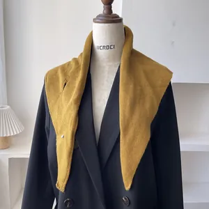 Detalle de bufanda triangular de lana amarillo jengibre sobre un blazer negro