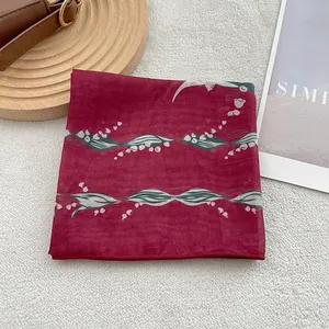 Detail of burgundy floral scarf featuring delicate lily of the valley pattern on soft fabric