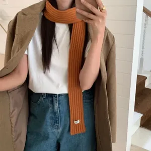 Vibrant orange ribbed knit skinny scarf for women styled with a winter coat and denim
