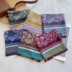 Multiple paisley printed silk scarves in various colors on a warm wooden background