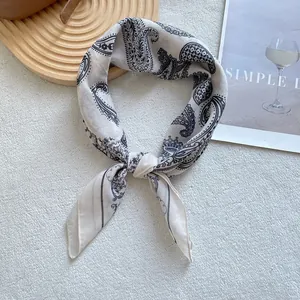 Macro detail of beige paisley silk square scarf with rolled edges and black print