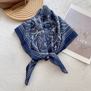 Detail of navy blue cotton blend square scarf with paisley pattern on wooden tray