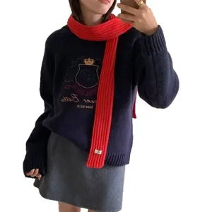 Navy collegiate knit sweater with shield embroidery and vibrant red knitted long scarf