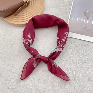Detailed flat lay of dark red linen scarf with elegant floral prints and a smooth texture