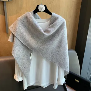 Detail of grey wool knit shawl with speckled texture and white laundry care label