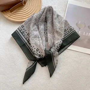 Detailed view of vintage paisley square scarf in grey and dark green tones on textures