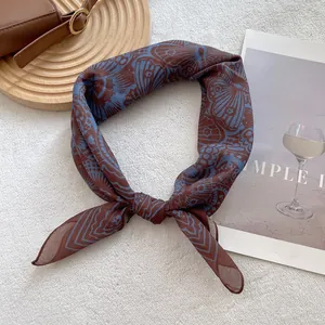 Detailed shot of retro totem square scarf with brown and blue butterfly print and silky texture