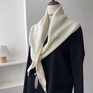 Detailed macro view of the rib-knitted cream white shawl draped on a black blazer suit