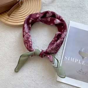 Silk square scarf with floral paisley patterns and geometric contrast colors tied in a knot