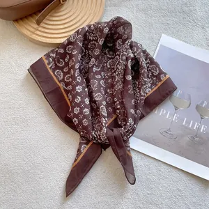 Elegant brown paisley silk scarf with orange piping on a textured background