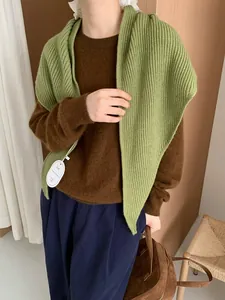Detail of grass green knitted shawl with thick ribbing and elegant brand tag on a model