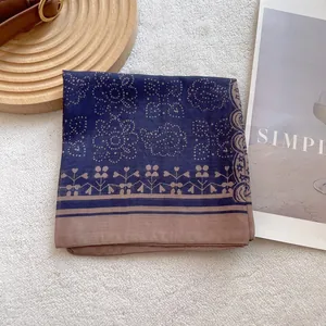 Detail of navy blue vintage paisley silk scarf with rolled edges on a wooden tray