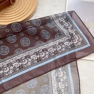 Detail shot of vintage coffee paisley silk scarf with intricate floral print and soft edges