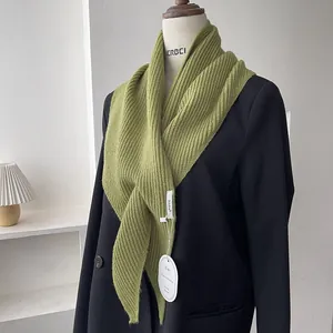Detail of green knitted scarf with ribbed texture on a black suit jacket for women