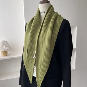 Detail of green knitted triangle shawl with ribbed texture on a black blazer mannequin