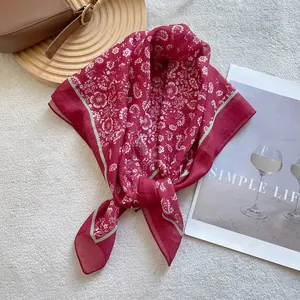 Macro shot of red paisley silk scarf with green stripes on vintage flatlay background
