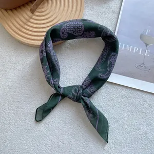 Macro shot of dark green paisley silk scarf with purple pattern on wooden tray